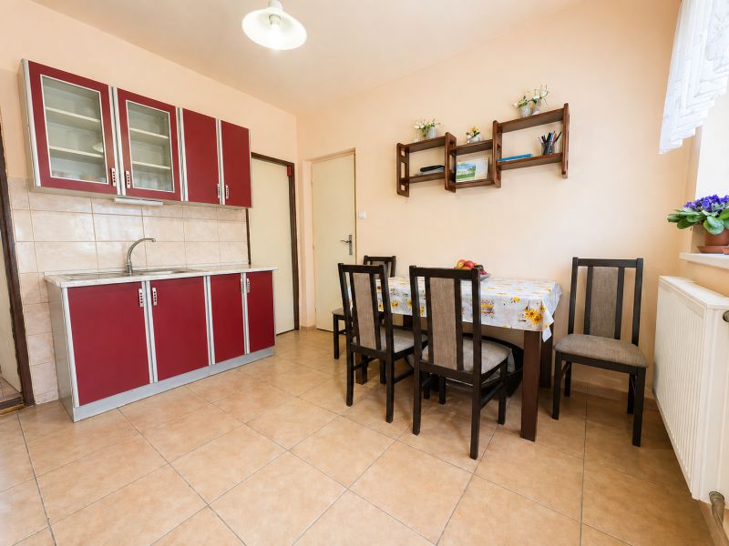 A kitchen and dining area in a family house with a red kitchen unit and table.