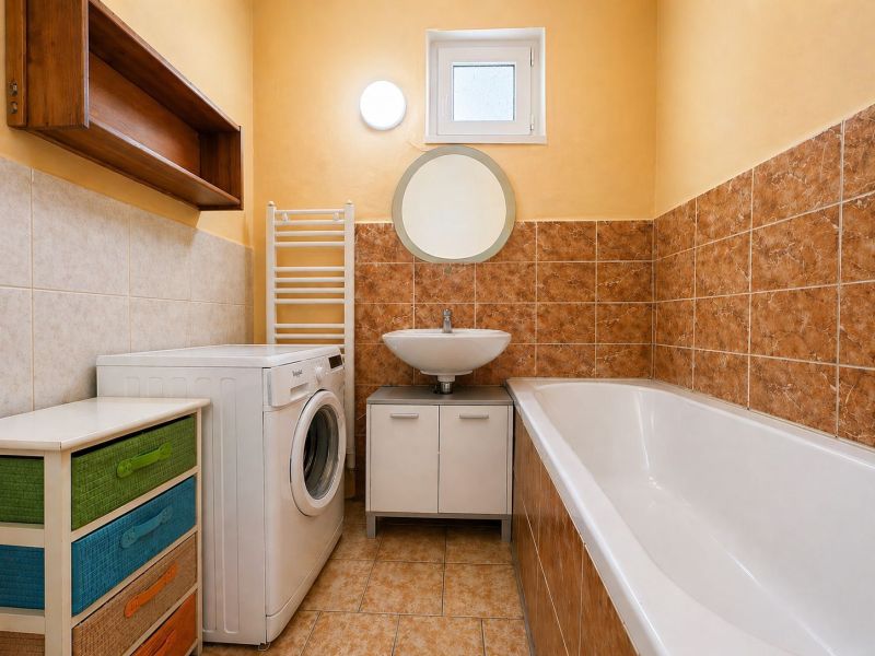 A bathroom with a bathtub, a washing machine, and a colorful dresser in a family house.