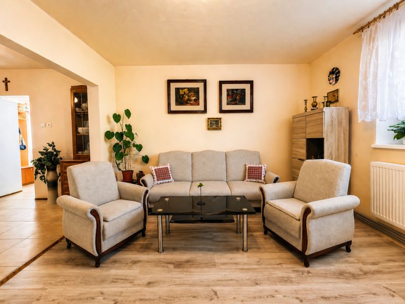 Living room with a sofa, armchairs, a glass table, and a wooden decor floor.