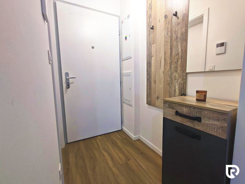 Entrance hallway in a 2-room apartment with a wooden decor floor and a coat rack wall.