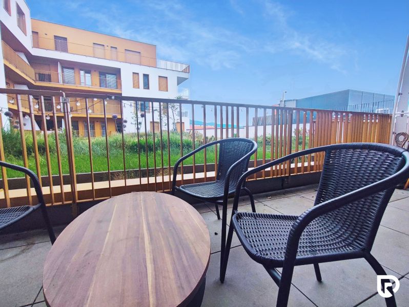 A balcony with rattan seating and a view of the architecture of Piaristická Street in Nitra.