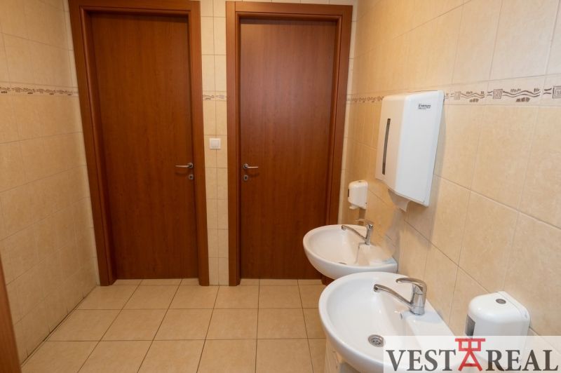 Office restroom with two sinks and a door, tiled with ceramic tiles.
