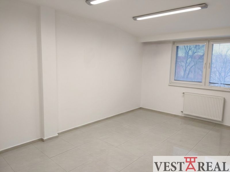Bright room in an office with white walls, a window, and a tiled floor.