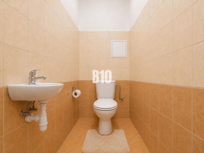 Bathroom in a 2-room apartment with a toilet, sink, and tiles.