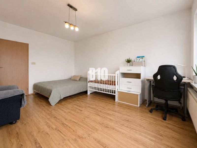 Children's room in a two-room apartment with a bed, a desk, and a wooden decor floor.