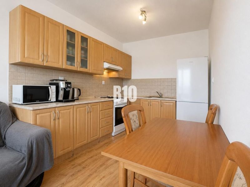 A kitchen in a 2-room apartment with wooden decor furniture and flooring, appliances in the corner.