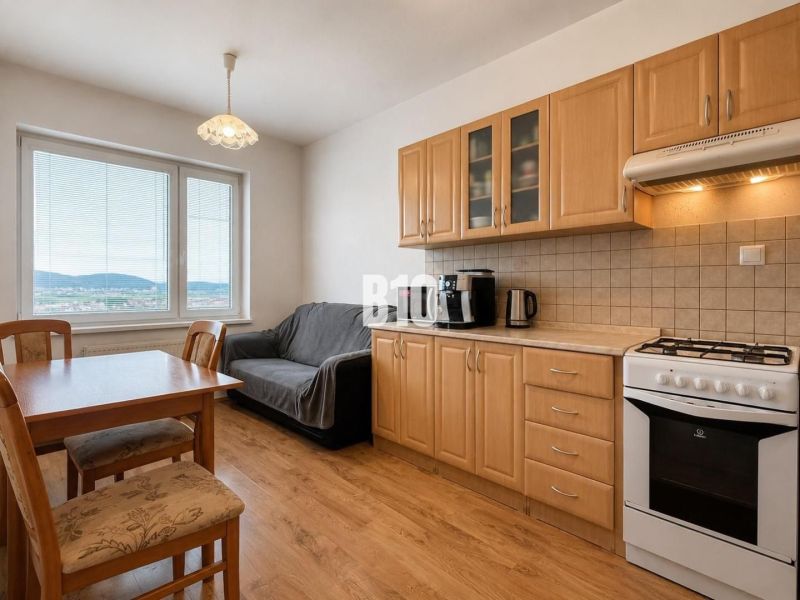 A kitchen in a 2-room apartment with a wooden decor floor and a dining table.