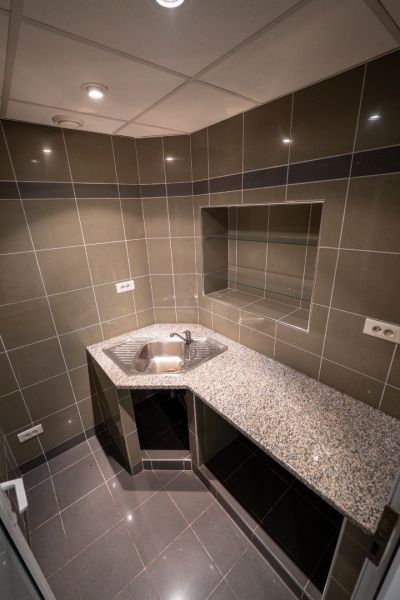 A kitchenette in a building with tiling, a sink, and a granite countertop.