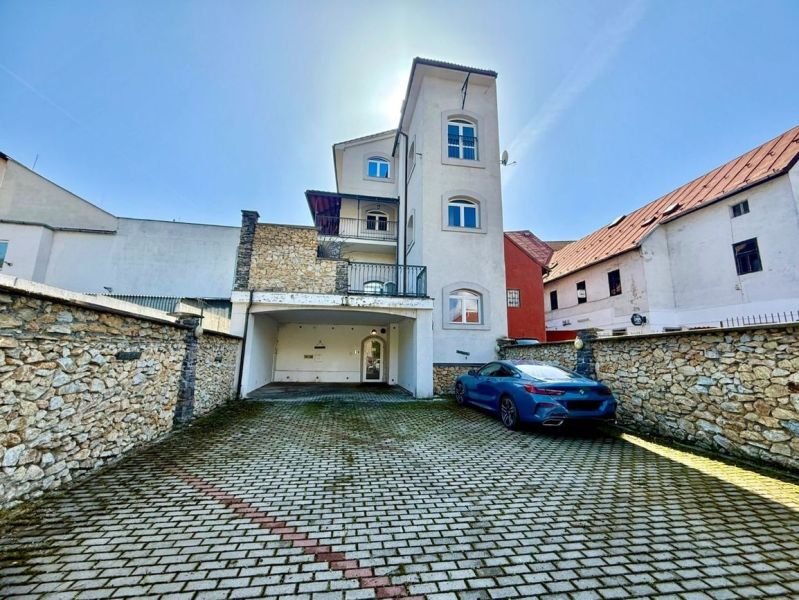 The building on Dolná Street 28 in Banská Bystrica with a parking lot and a stone wall.