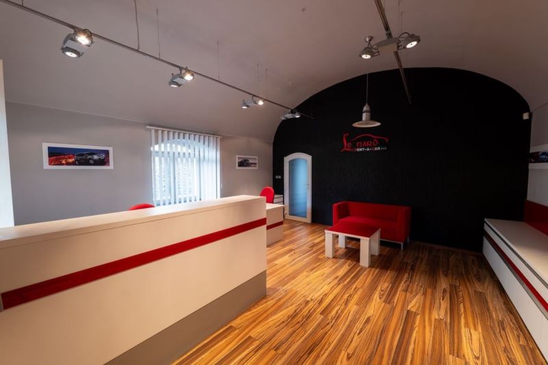 Reception with a wooden decor floor. Red elements on a dark wall. Building.