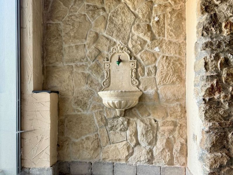 Stone wall with a decorative fountain and a faucet.