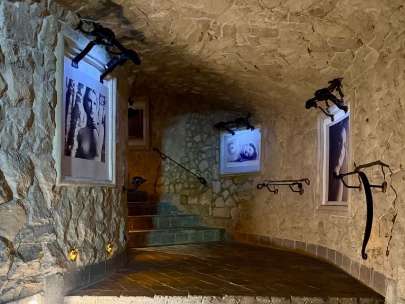 Stone stairs with decorated walls featuring black and white photographs in the interior of the building.