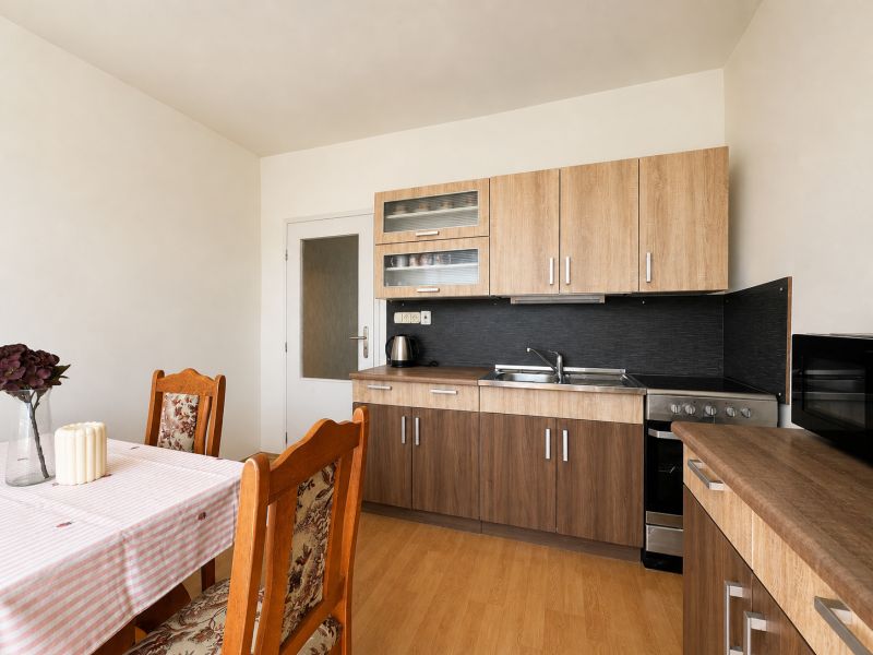 A kitchen in a studio apartment with wooden furniture and flooring, dining table.