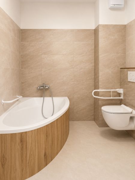Bathroom with a bathtub and toilet in a 2-room apartment, tiles in a beige shade.