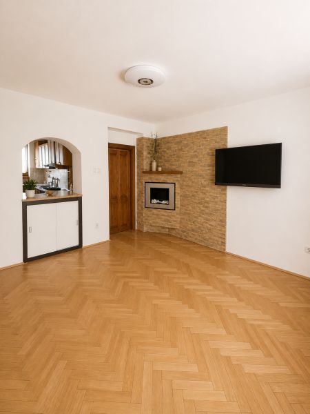 A room with a TV on the wall, a fireplace, and a wooden decor floor.