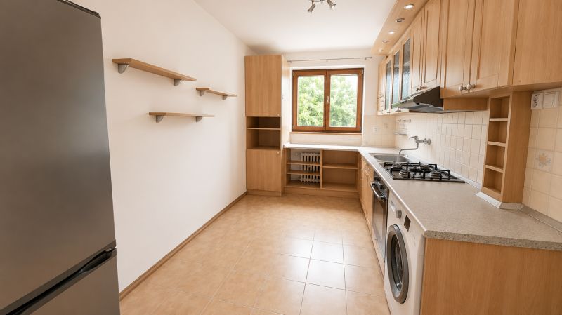A kitchen in a 2-room apartment with wooden cabinets, appliances, and a window.