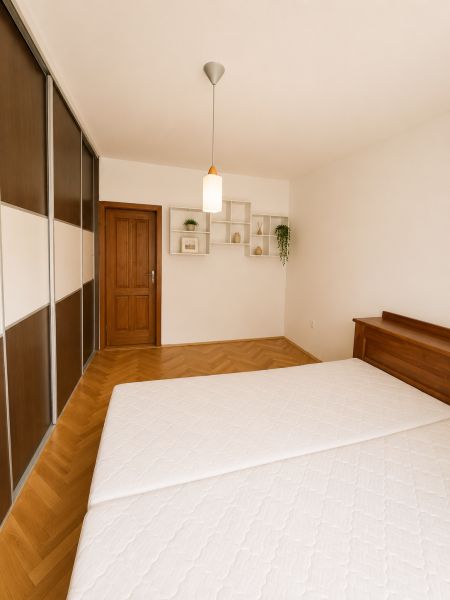 Bedroom in a 2-room apartment with a wood-patterned floor and a built-in wardrobe.