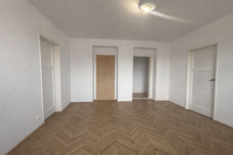 Interior of a 2-room apartment with white walls and a floor with a wooden decor.