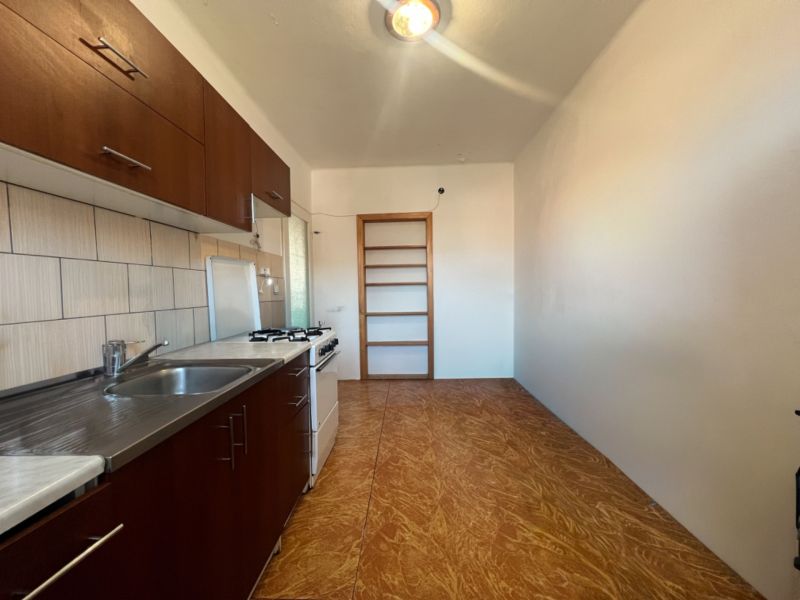 A kitchen in a 2-room apartment with a kitchen unit and a floor with a wooden decor.