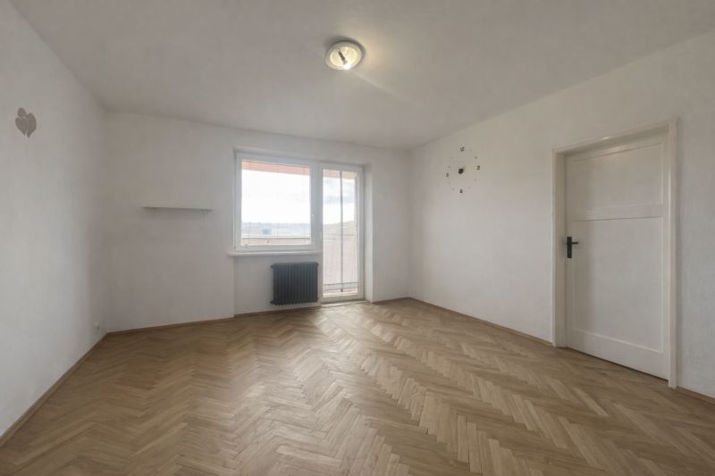 An empty room with white walls and a wooden decor floor in a two-room apartment.