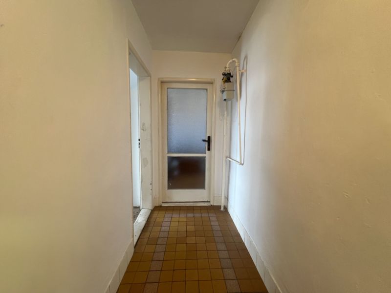 A hallway in a 2-room apartment with tiles and white walls.
