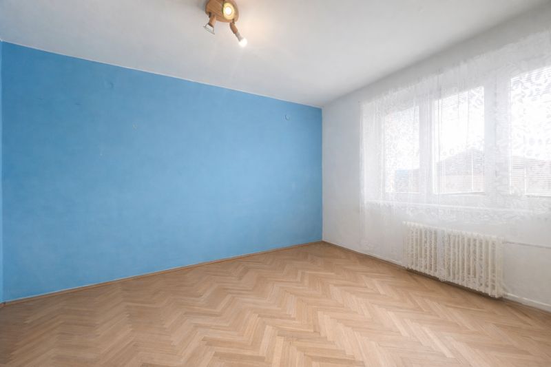 A room in a 2-room apartment with a blue wall and a wooden decor floor.