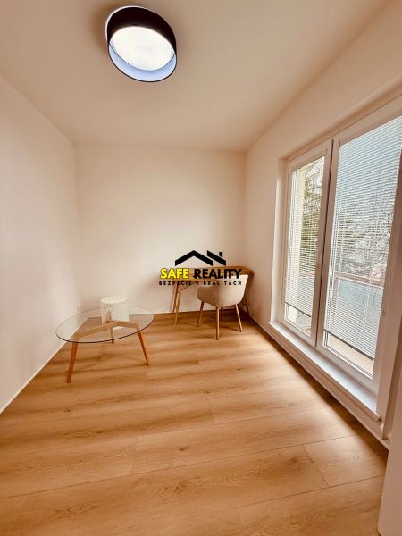 A room in a 3-room apartment with a wooden decor floor, a table, and a chair.