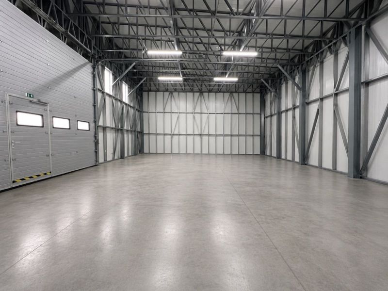 Empty manufacturing spaces with steel structure and concrete floor.