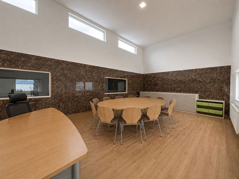 An office with a wood-patterned floor, a round table, and cabinets in the production area.