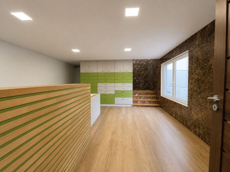 Production premises with a wooden decor floor, a green and white cabinet, and a window.