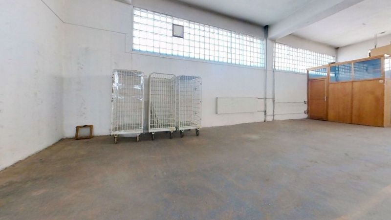 Warehouses and halls with empty space, sliding trolleys, and a glass partition.