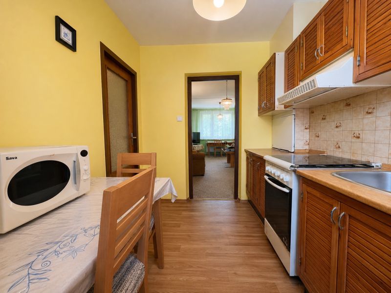 A kitchen with a microwave and a wooden decor floor in a 2-room apartment.