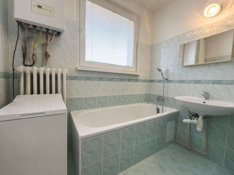 Bathroom in a 2-room apartment with a bathtub, sink, and washing machine.