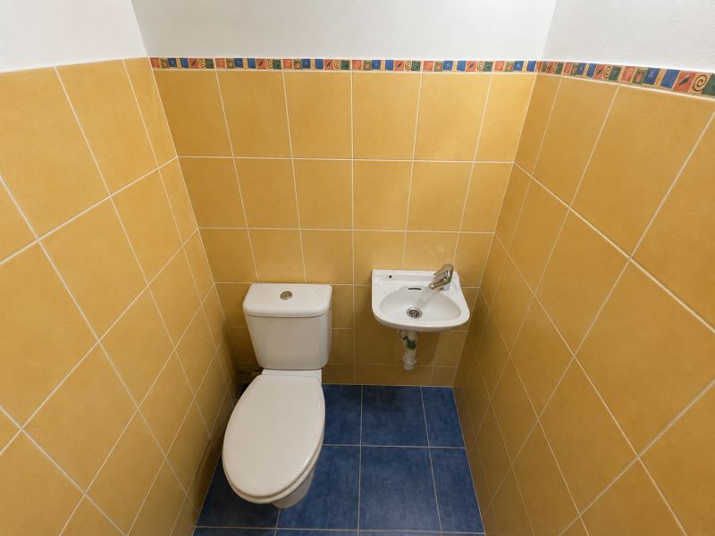 Toilet with a sink in a bathroom with colorful tiles in a 2-room apartment.