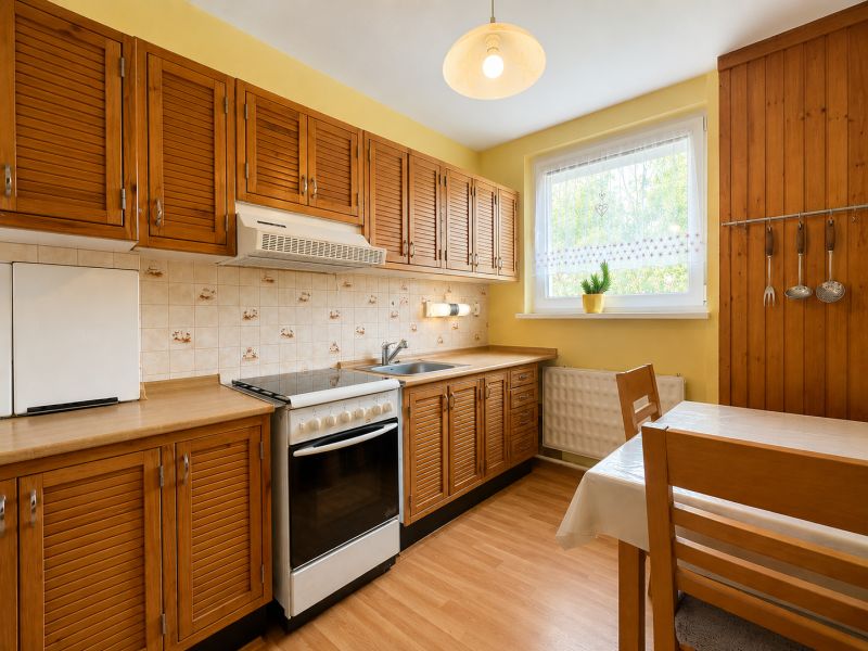 A kitchen in a two-room apartment with a kitchen unit and a wooden decor floor.