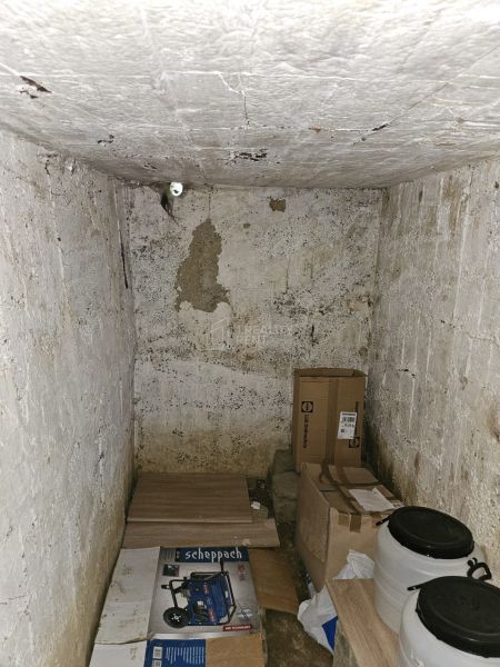 Storage space in a cabin with various boxes and plastic barrels on the floor.