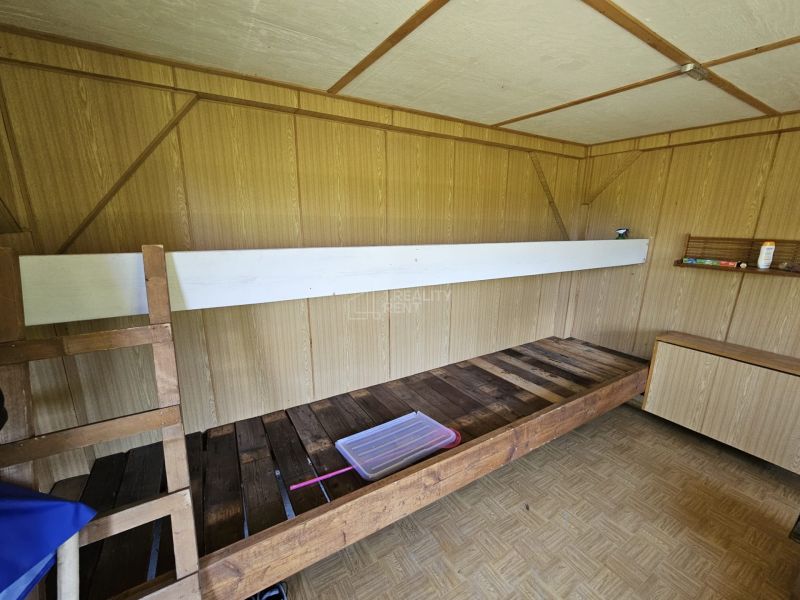 Interior of a cabin with a bunk bed, wooden decor flooring, and a wooden wall.