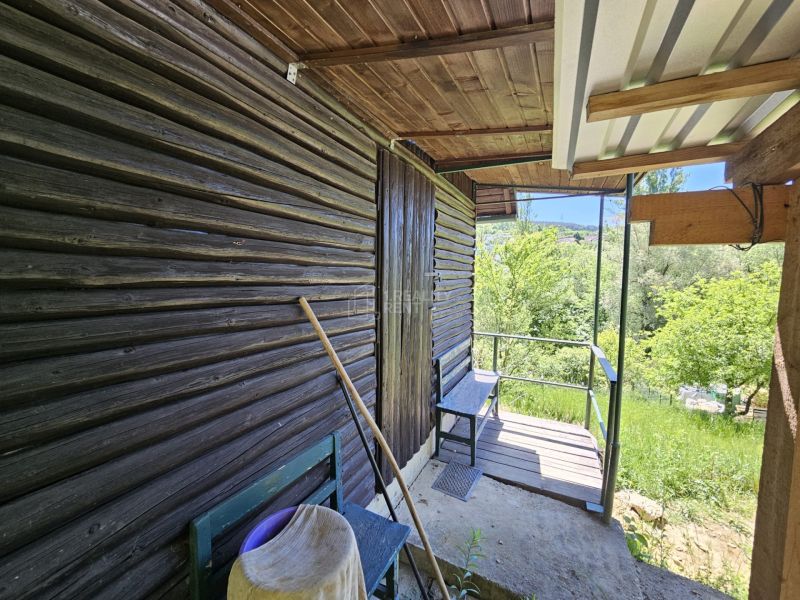 A cottage in Budatín with wooden cladding, a terrace, and a view of the green garden.