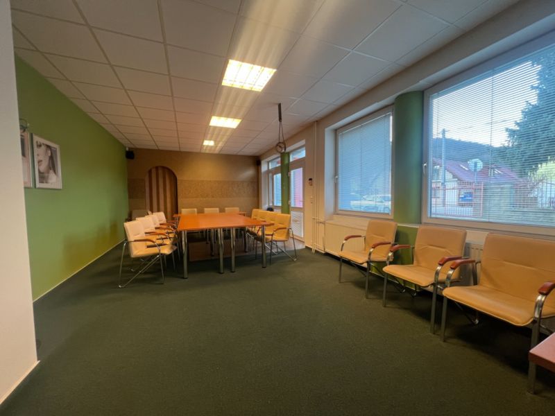 Room with a conference table and chairs, large windows, wooden decor flooring.