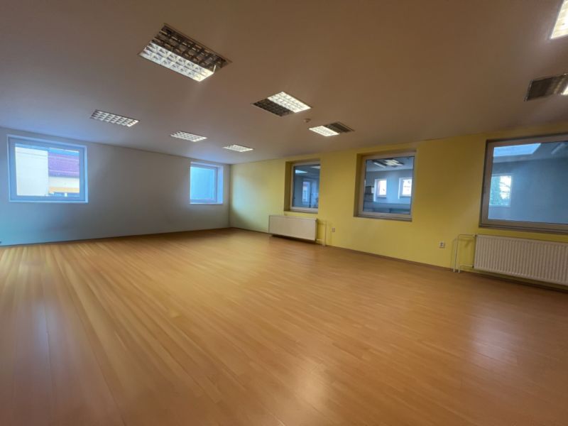 Interior of a production space with large windows, yellow walls, and a floor with a wooden decor.