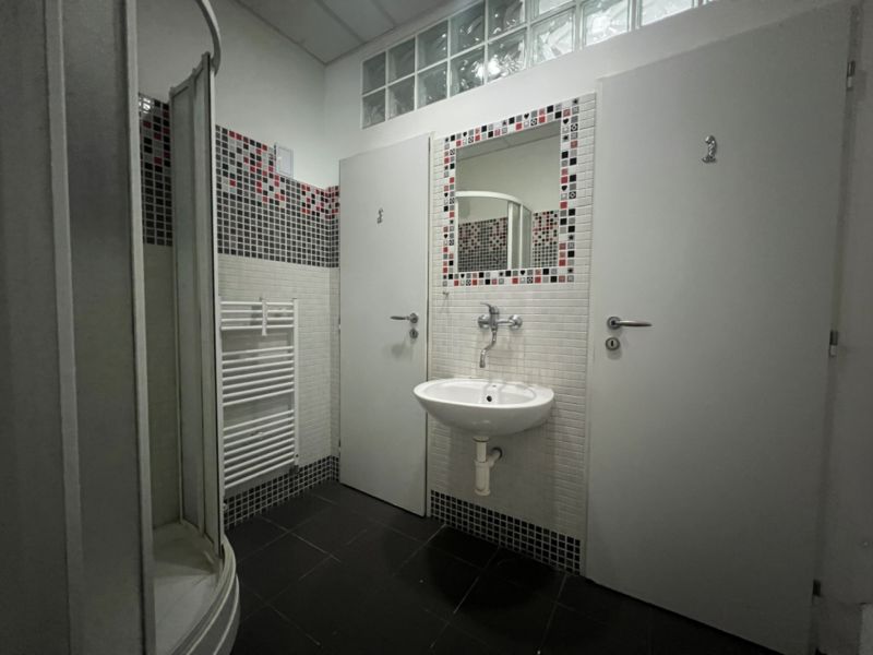 Bathroom with a sink, shower, mirror, and door in warehouses and halls.