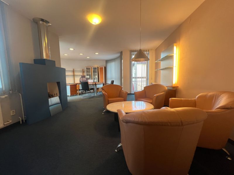Interior of manufacturing spaces with a fireplace, leather armchairs, and a coffee table.