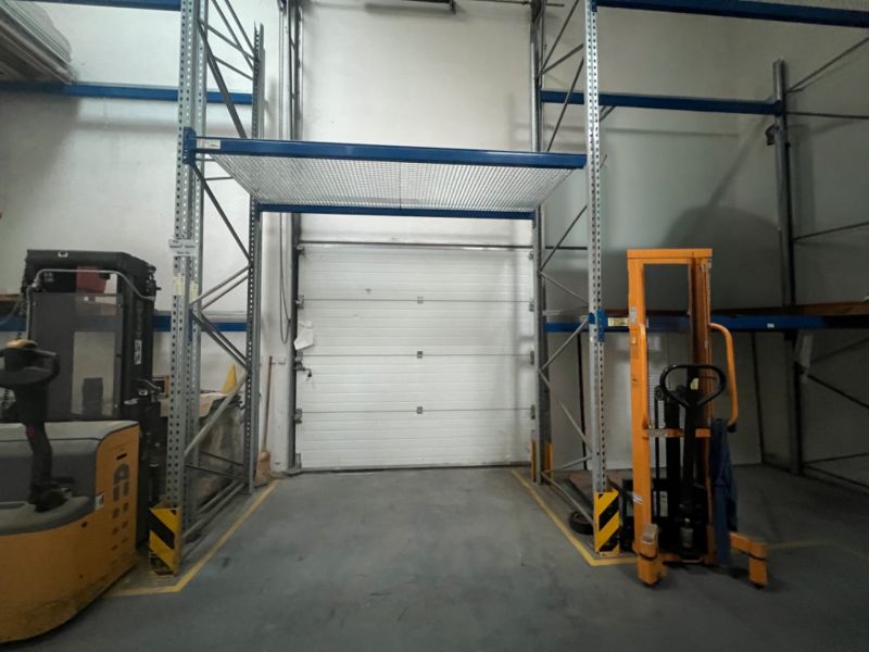 Warehouses and halls with shelves, a forklift, and a closed garage door.