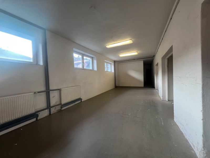 A long room with white walls, windows, and cast iron radiators in warehouses and halls.
