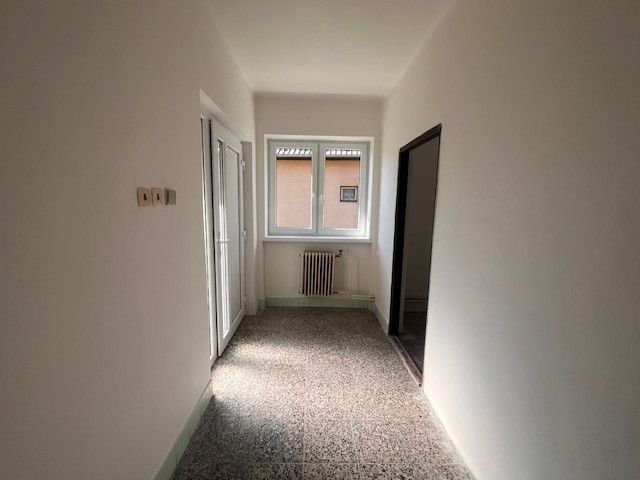 Interior of a family house with white walls, a radiator, and a large window.