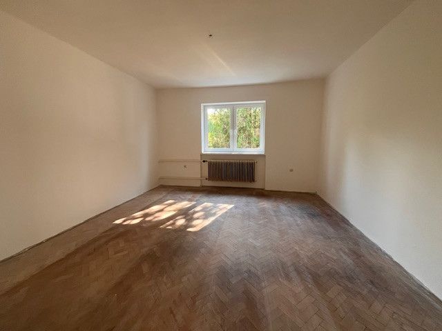 A spacious room in a family house with a wooden decor floor and a large window.
