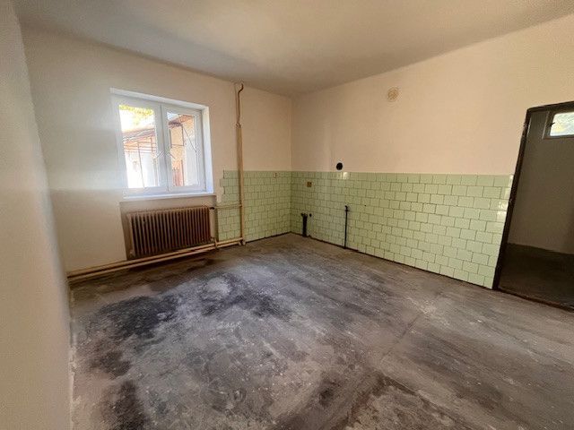 A room in a family house with a window, a radiator, and light green tiles.