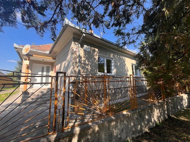 A family house in Vrakúňa with a decorative metal fence and trees in the background.