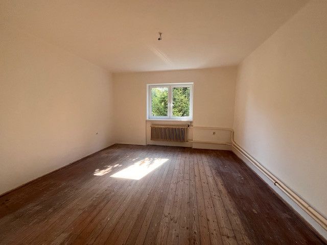 Interior of a family house with a wooden decor floor and a window overlooking greenery.