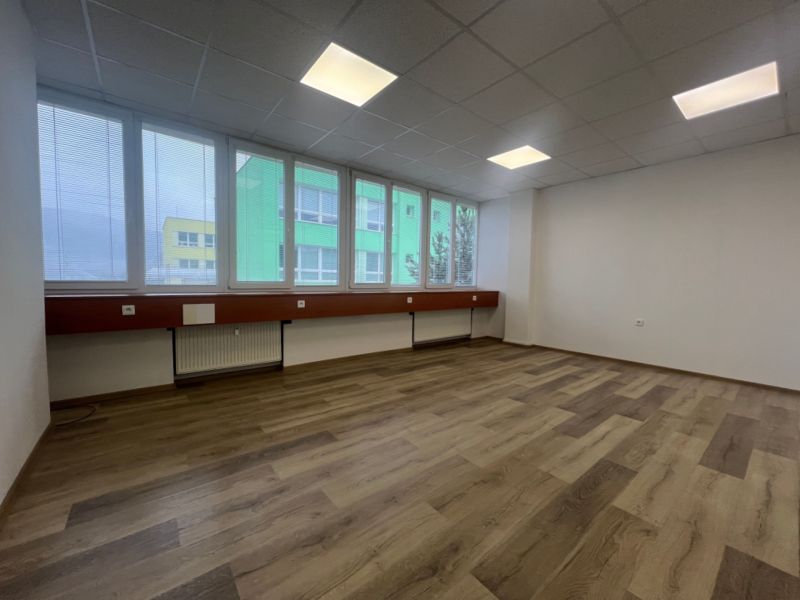Offices with large windows and wooden decor flooring.